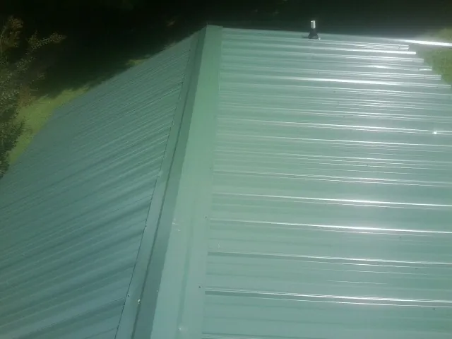 New green metal panels meeting at the ridge of a roof — Flat Roof Repair work by our crew in Antelope