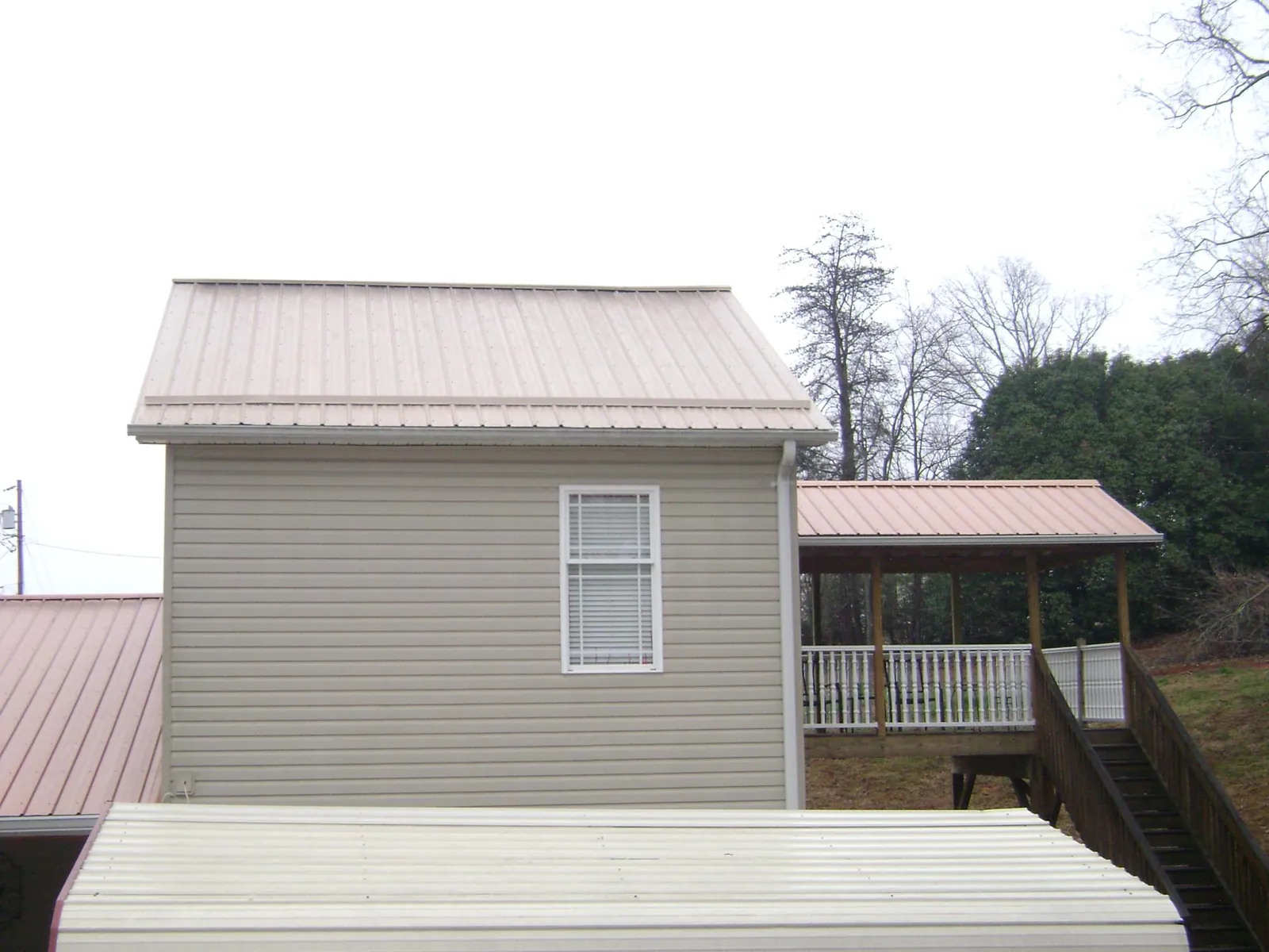 Tan metal roofs on a two story addition and attached porch, from a Roof Replacement job in Antelope